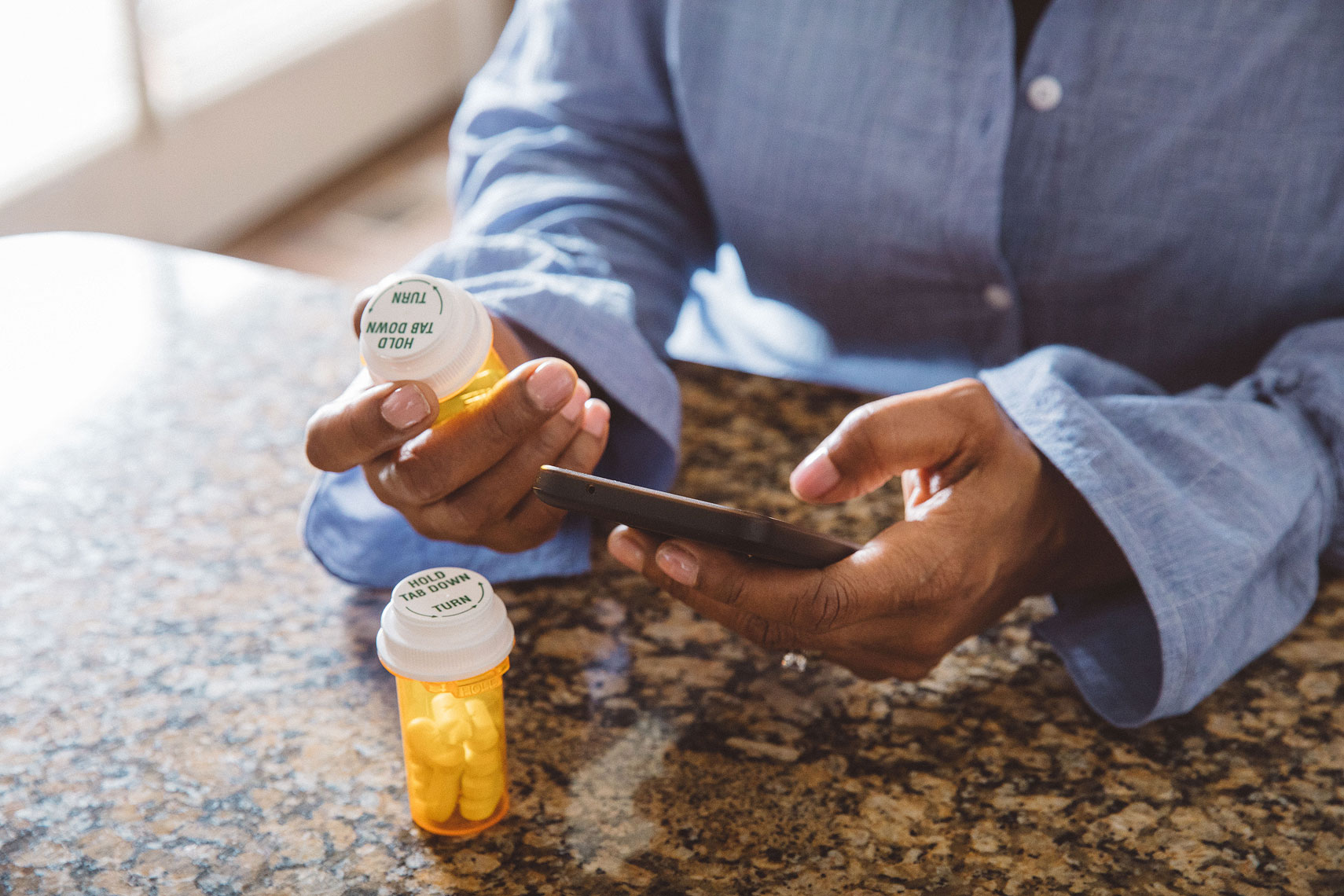 Woman holding a prescription bottle and a cell phone |  Centene | John Fedele Lifestyle Photography