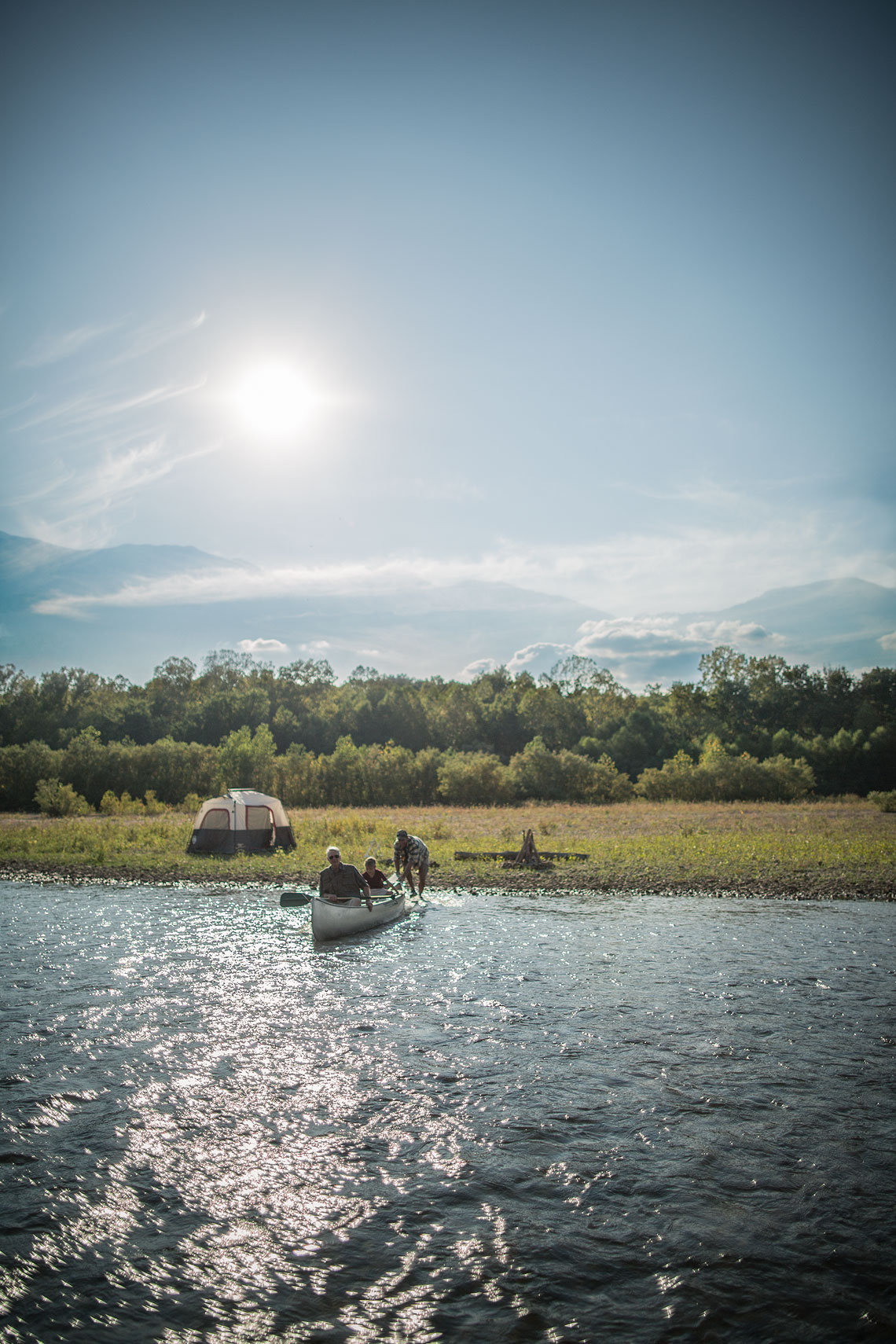 Family pushing out their canoe  into the water from their campsite. | John Fedele Lifestyle Photography