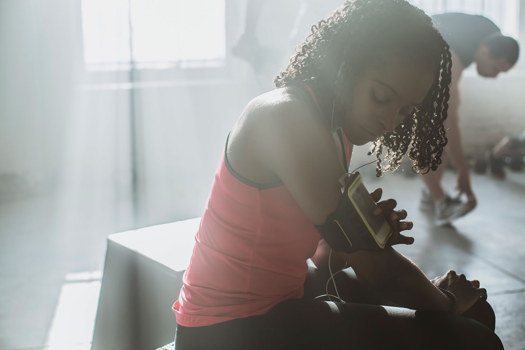 A woman in a gym adjusting her phone. | John Fedele Lifestyle Photography