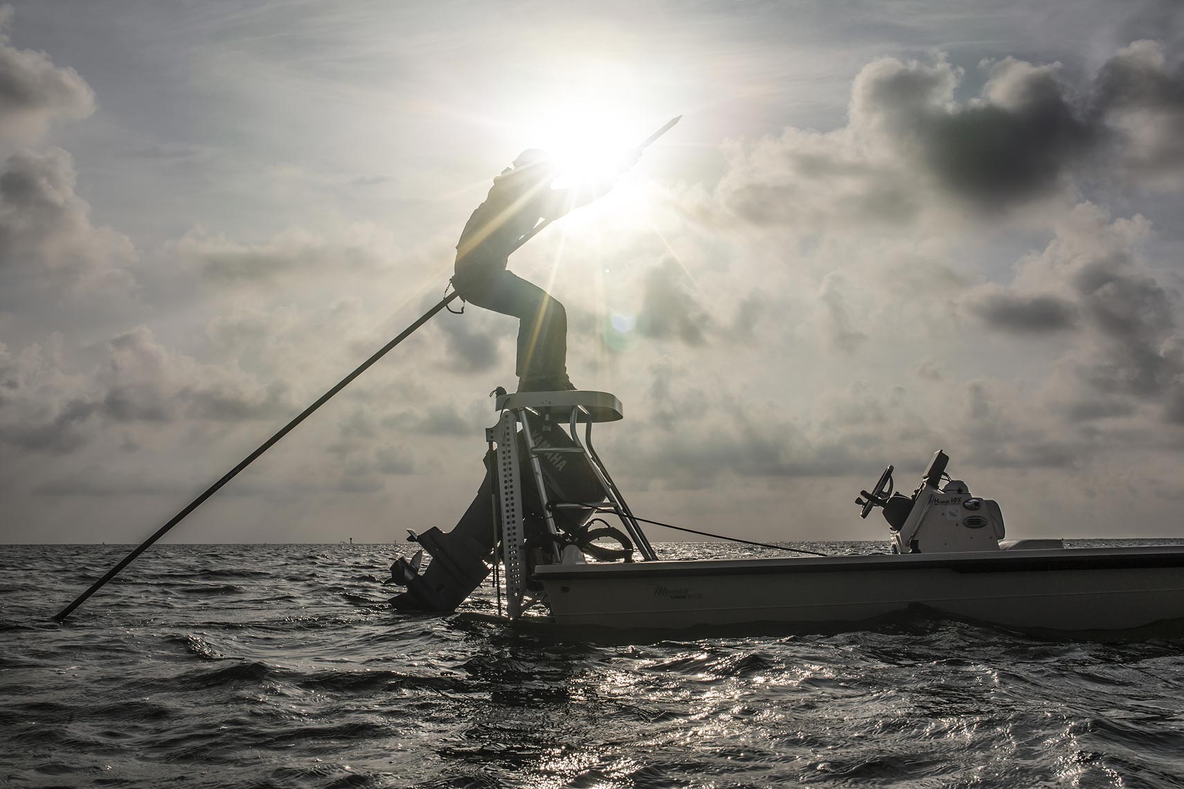 Man standing on a boat using an oar at sunset. | john Fedele Lifestyle Photography