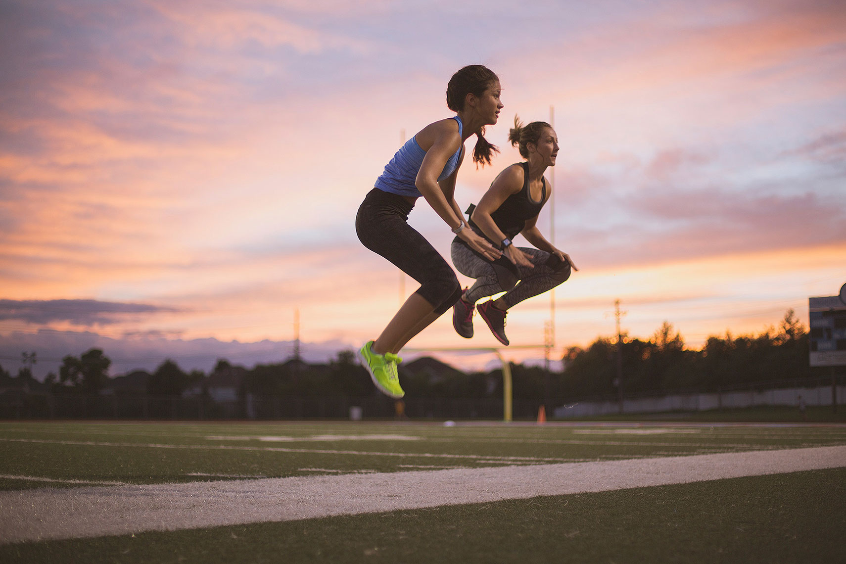 Two women doing jump squats at sunset on a track. | John Fedele Lifestyle Photography