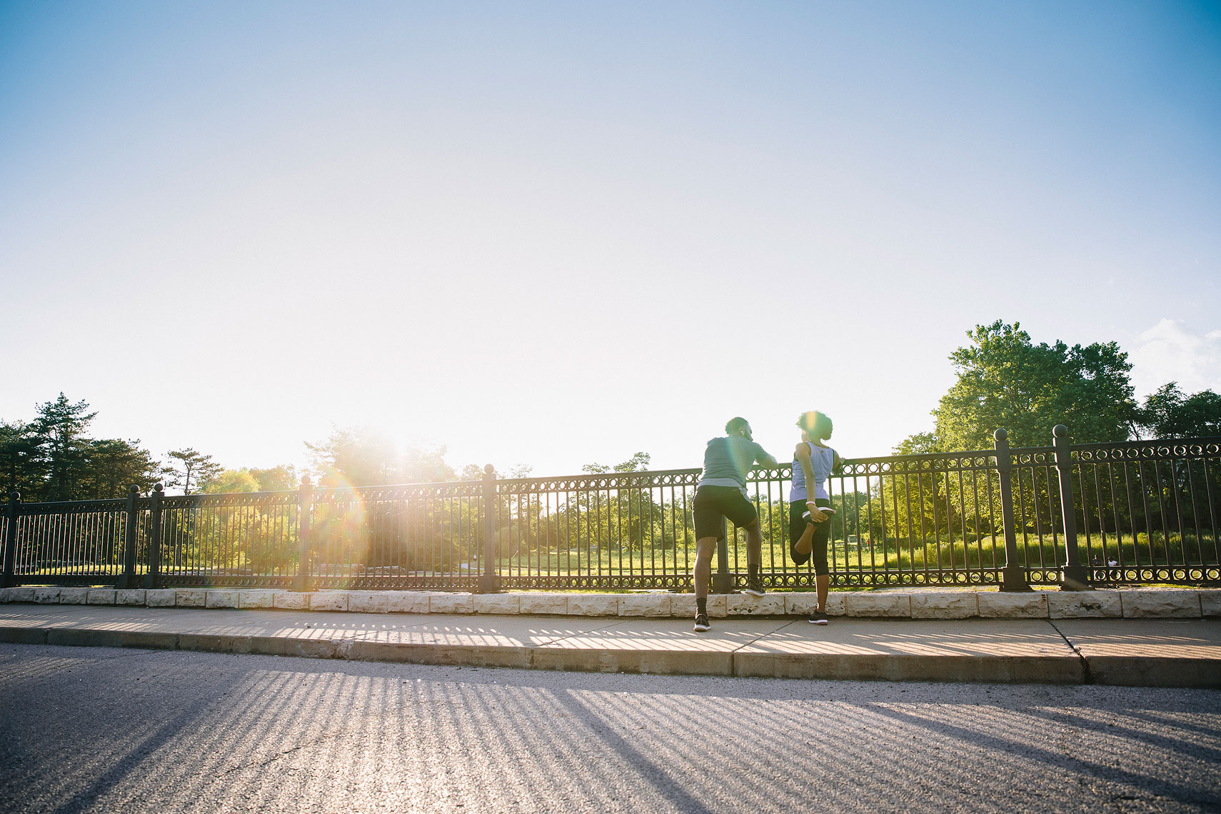 Two people standing at a fence stretching before a workout.  | John Fedele Lifestyle Photography